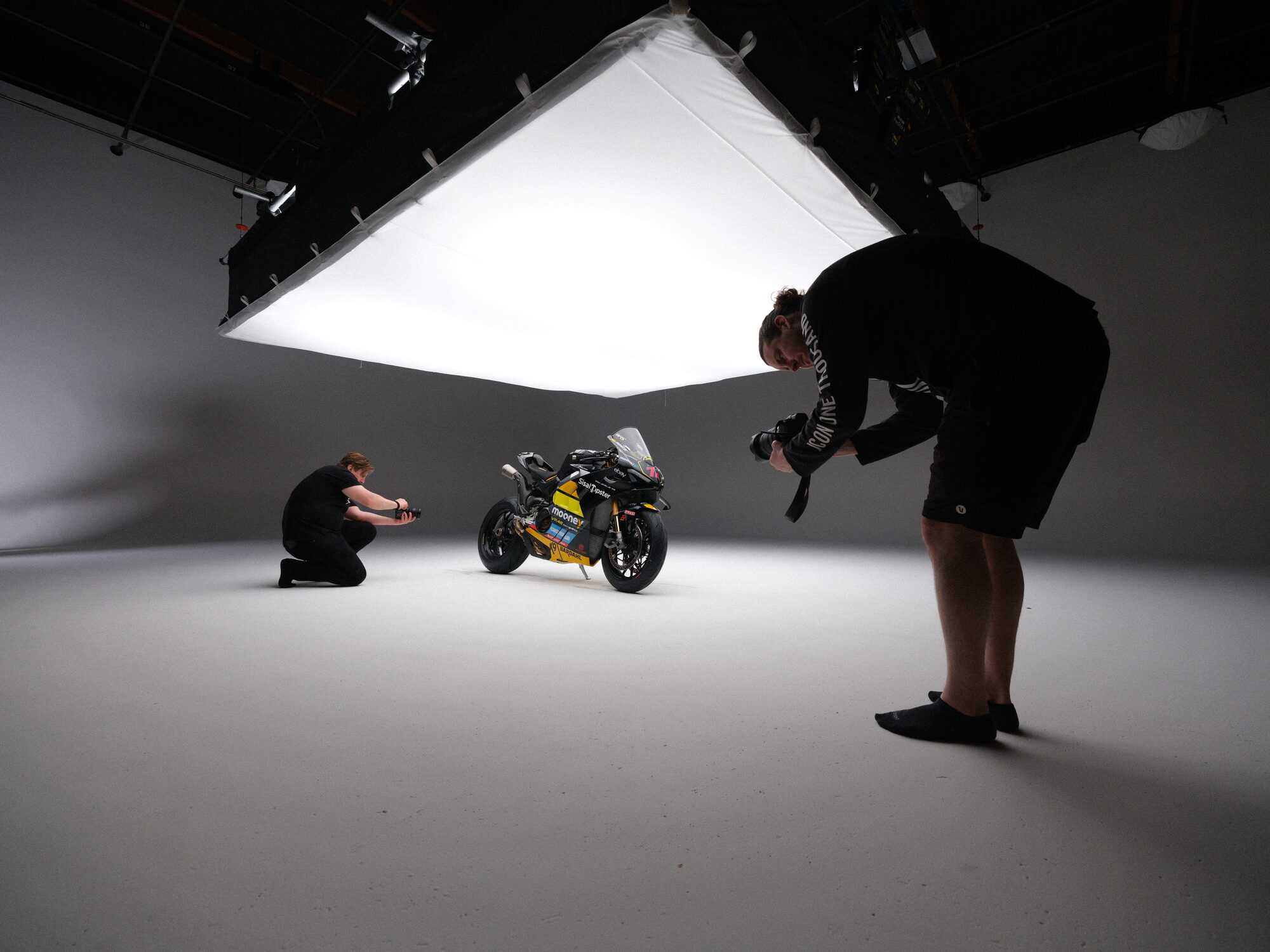 Two photographers shooting the race-liveried Ducati under the overhead softbox at Cine Rent West