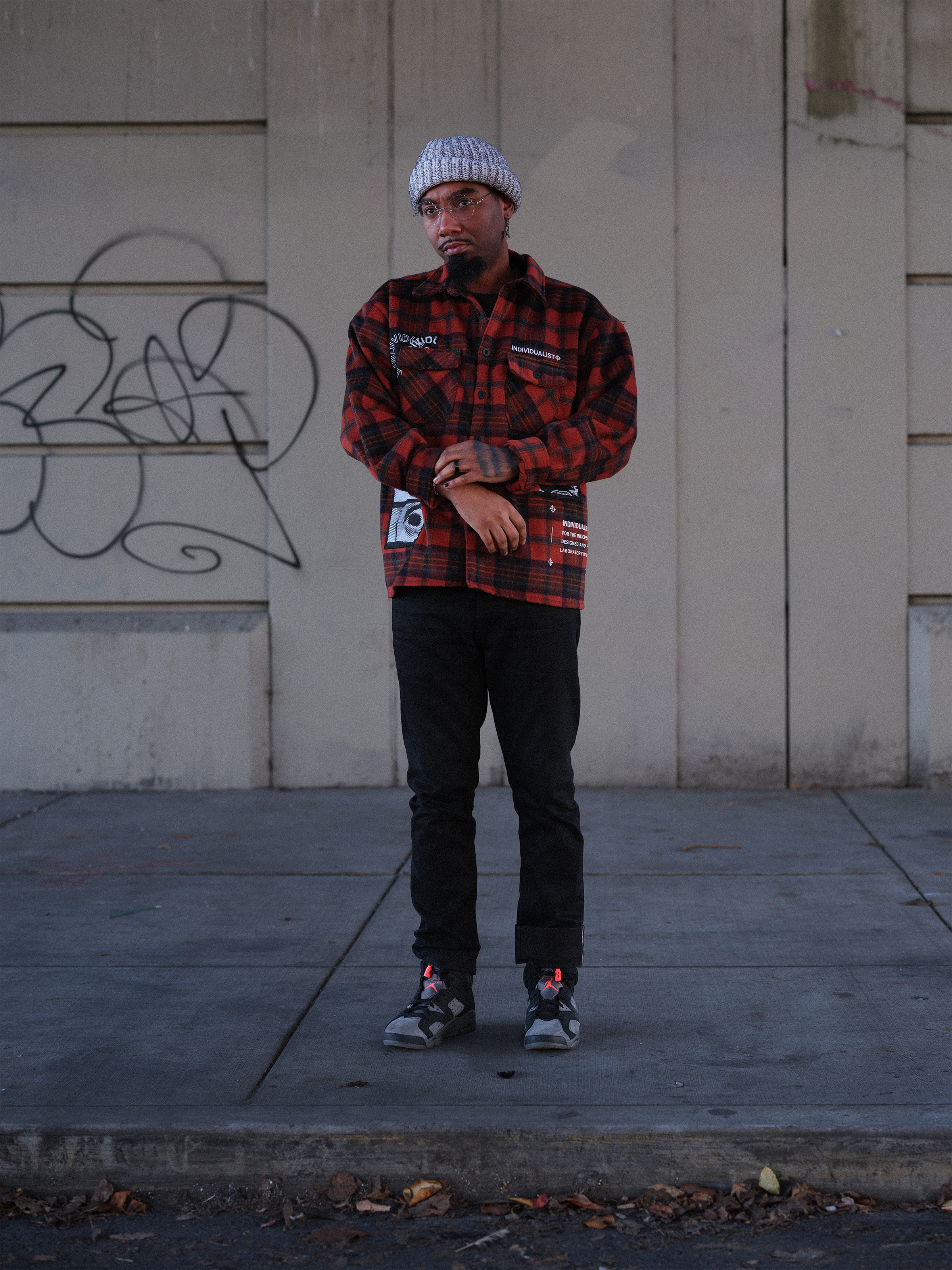 Street portrait, red flannel against graffiti wall