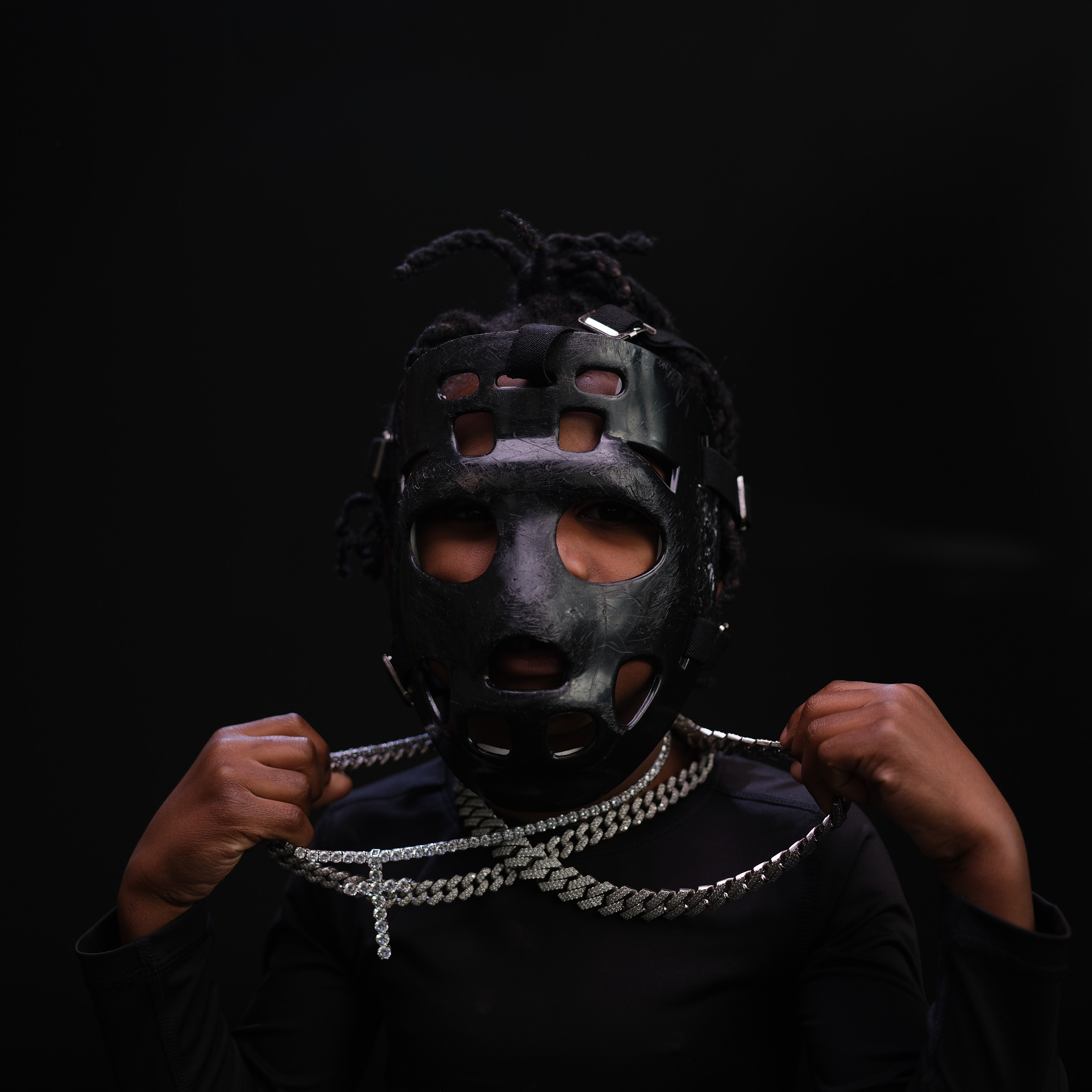 Portrait wearing goalie mask with layered chains