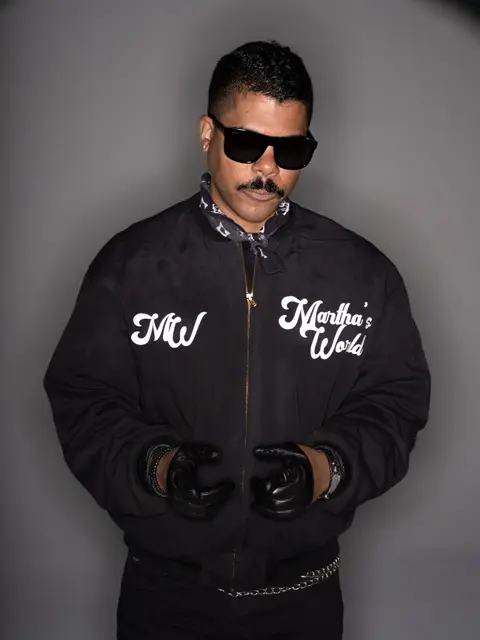 ILoveMakonnen in sunglasses and a black Martha's World jacket with leather gloves